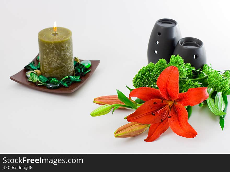 Red lily, green scented candle and black oil burner isolated on white background. Red lily, green scented candle and black oil burner isolated on white background.