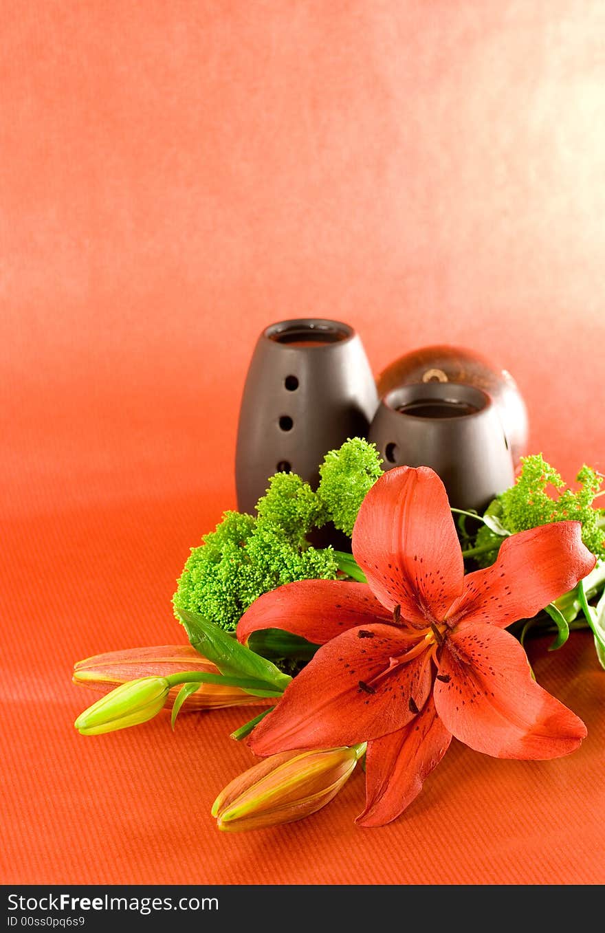 Red lily, red scented candle and black oil burner on red background. Red lily, red scented candle and black oil burner on red background.