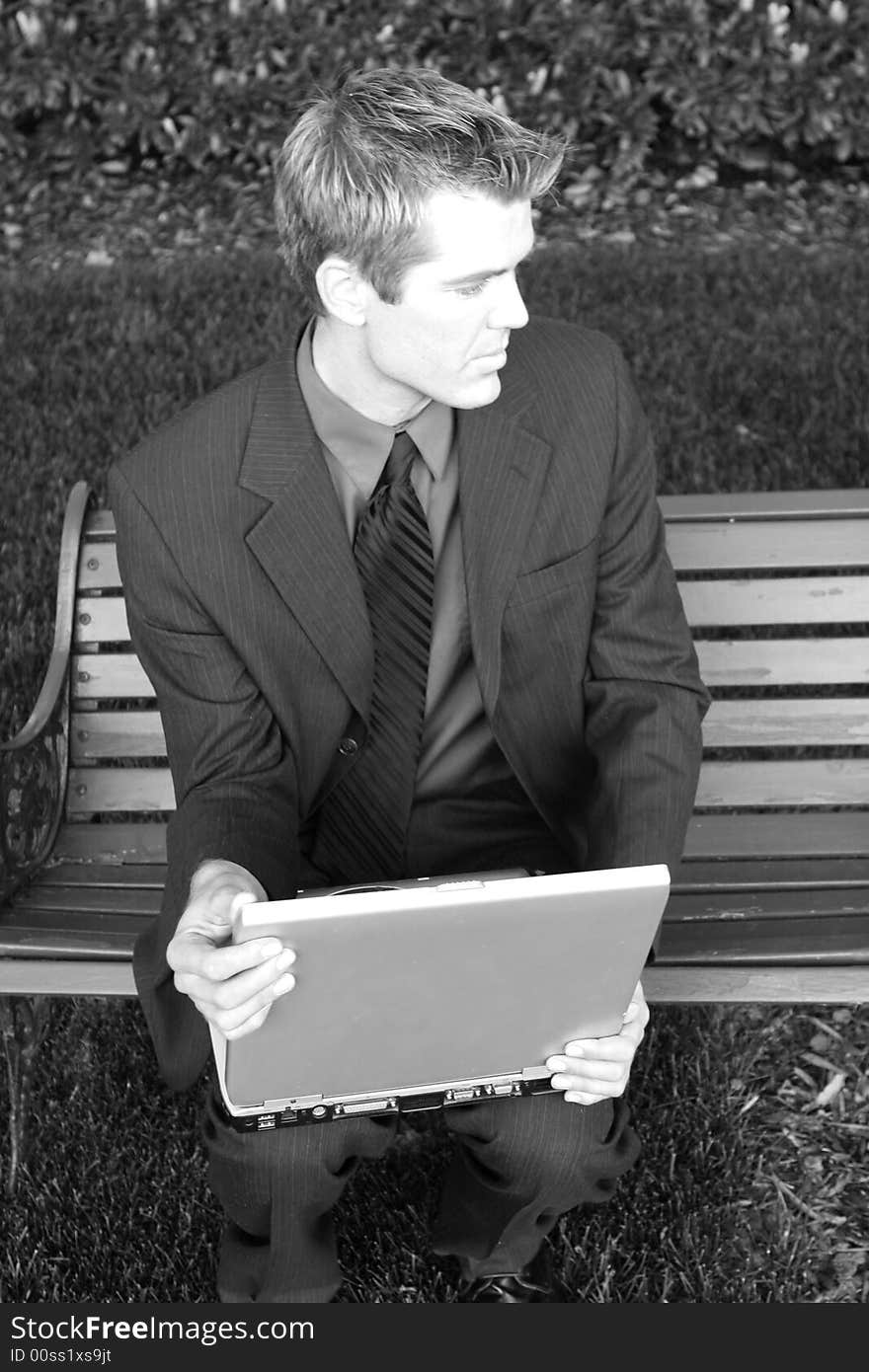 Front view of businessman sitting and holding laptop while looking away. Front view of businessman sitting and holding laptop while looking away