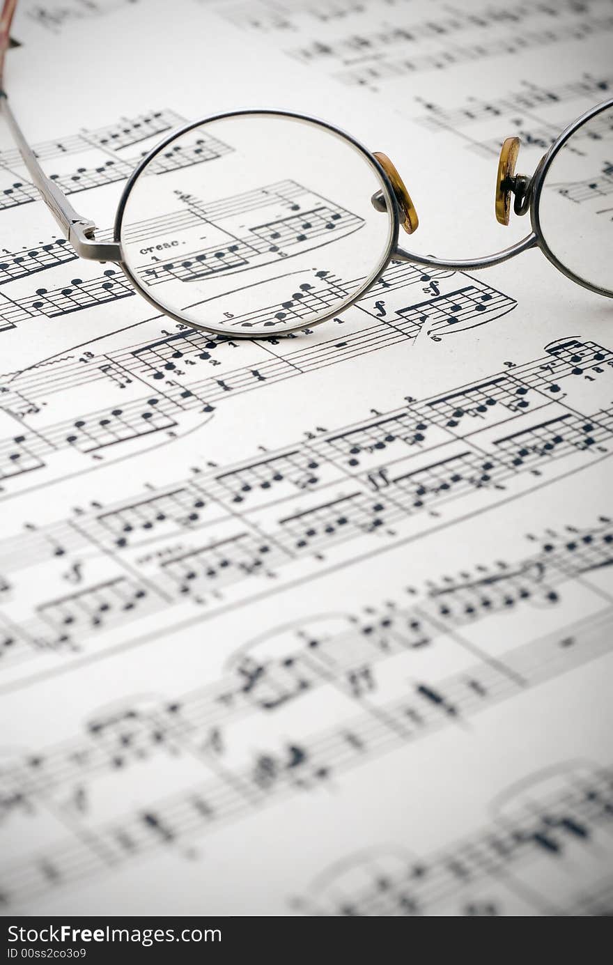 Old reading glasses resting on old sheet music. Old reading glasses resting on old sheet music