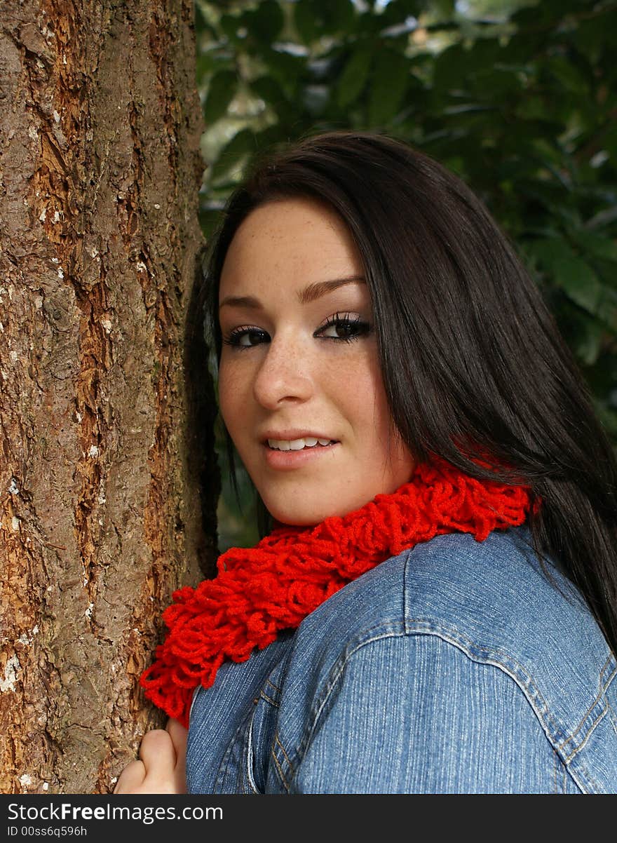 Close-up of attractive girl leaning against tree with wooded background. Close-up of attractive girl leaning against tree with wooded background