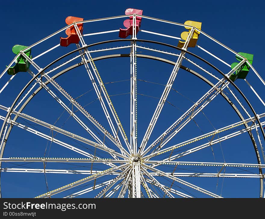 Colorful seats of the ferris wheel contrasted against a blue sky.