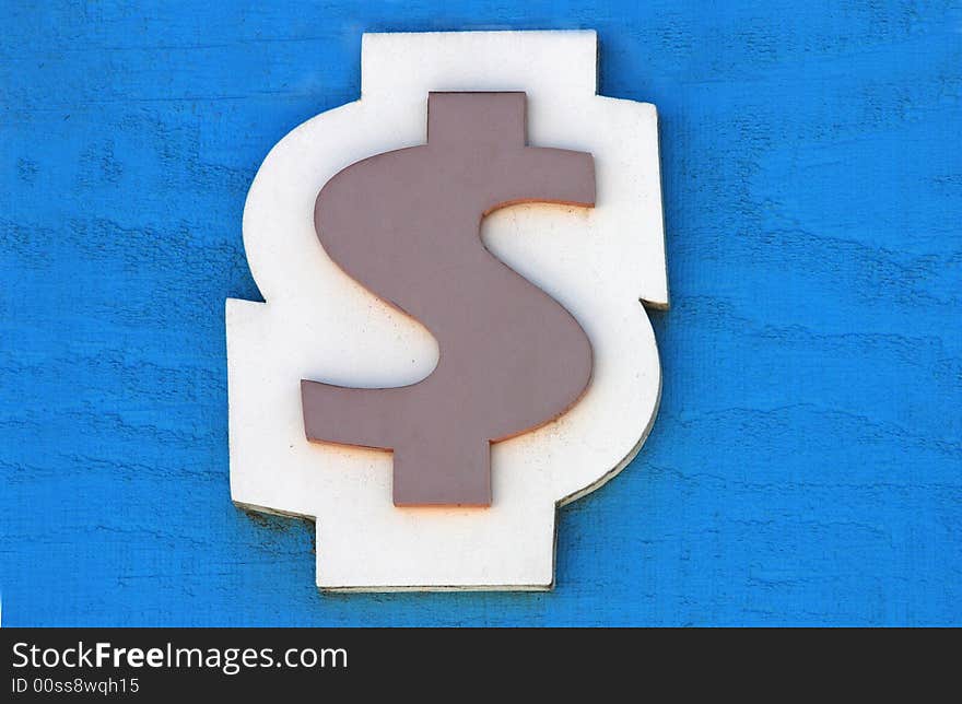 Wooden cut out dollar sign at a carnival against a blue background. Wooden cut out dollar sign at a carnival against a blue background