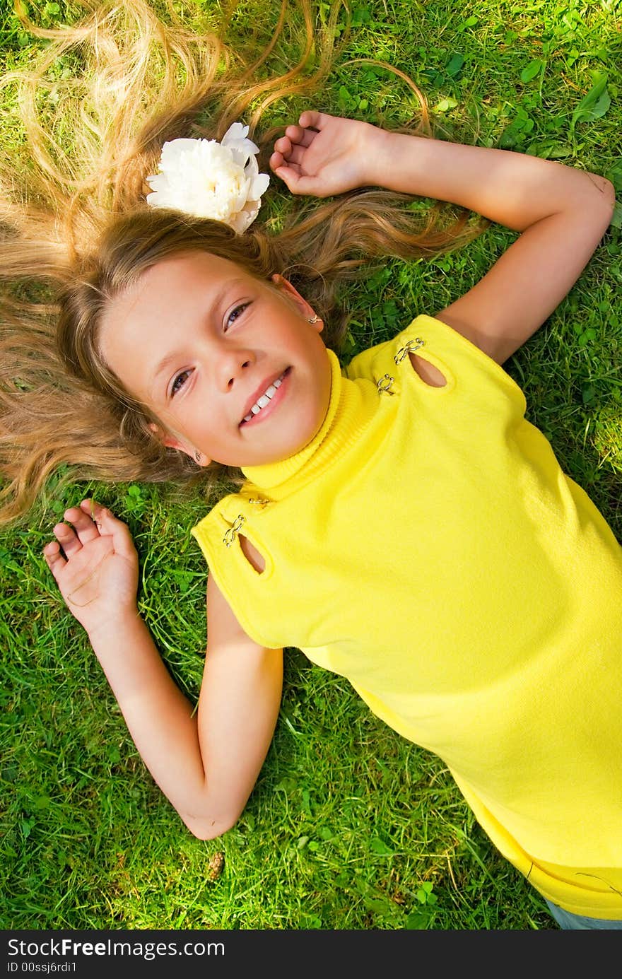 Happy young girl lying on a green grass