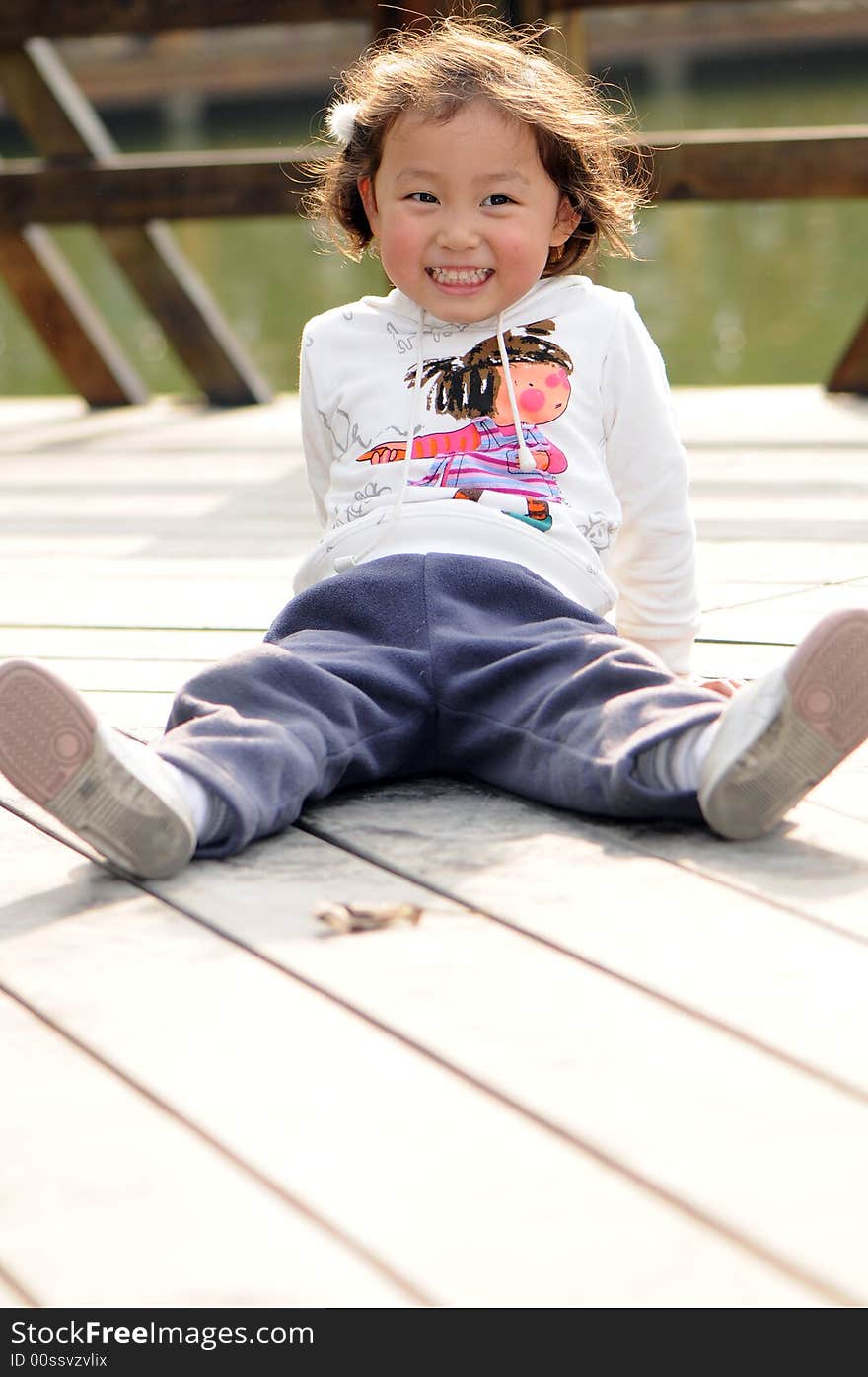 A little lovely girl sitting on the floor with a big smile.