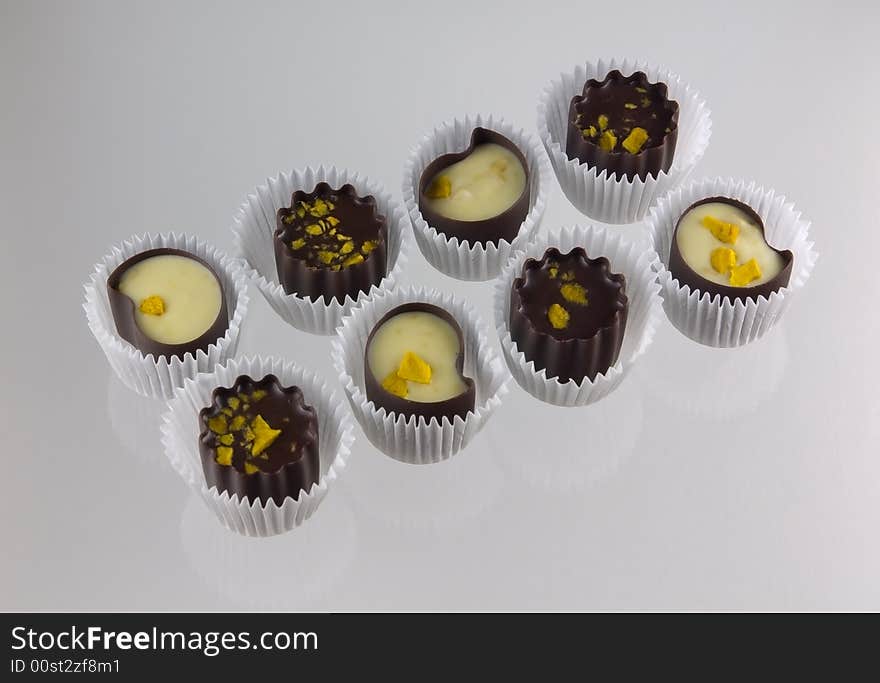 Chocolate candies from box, on glass. Light grey background.