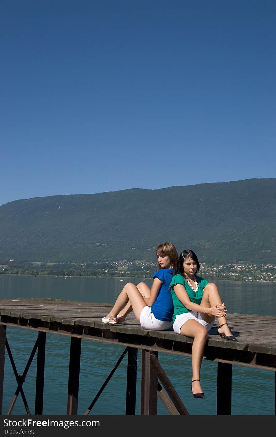 Young woman sitting on a pontoon at the edge of a lake. Young woman sitting on a pontoon at the edge of a lake