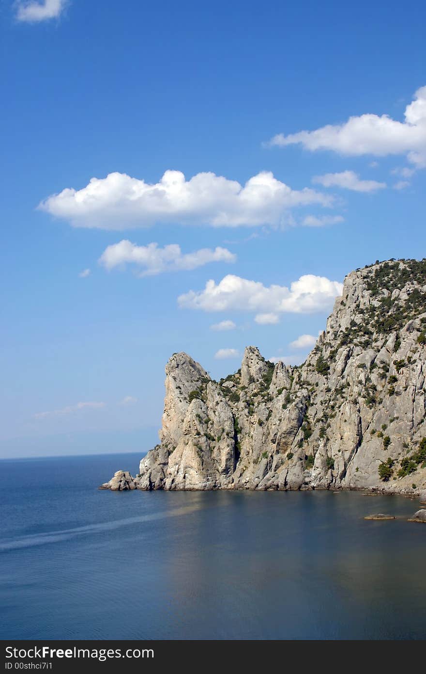 Rock on by sea, blue sky, clouds