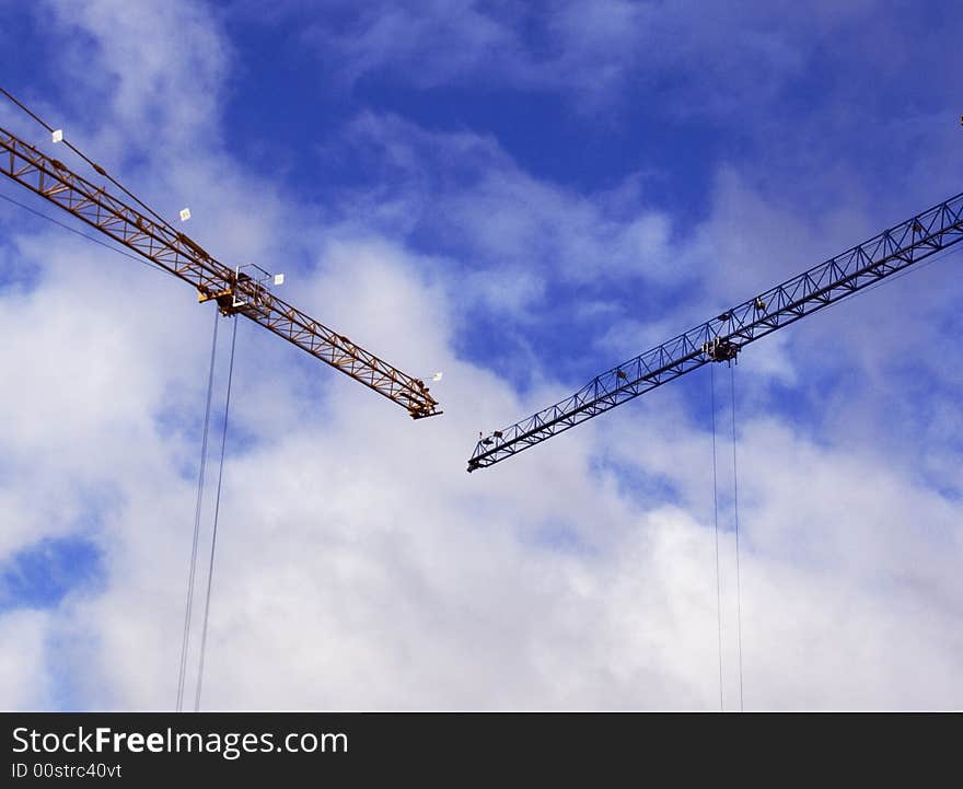 Two tower cranes on a background of the blue sky