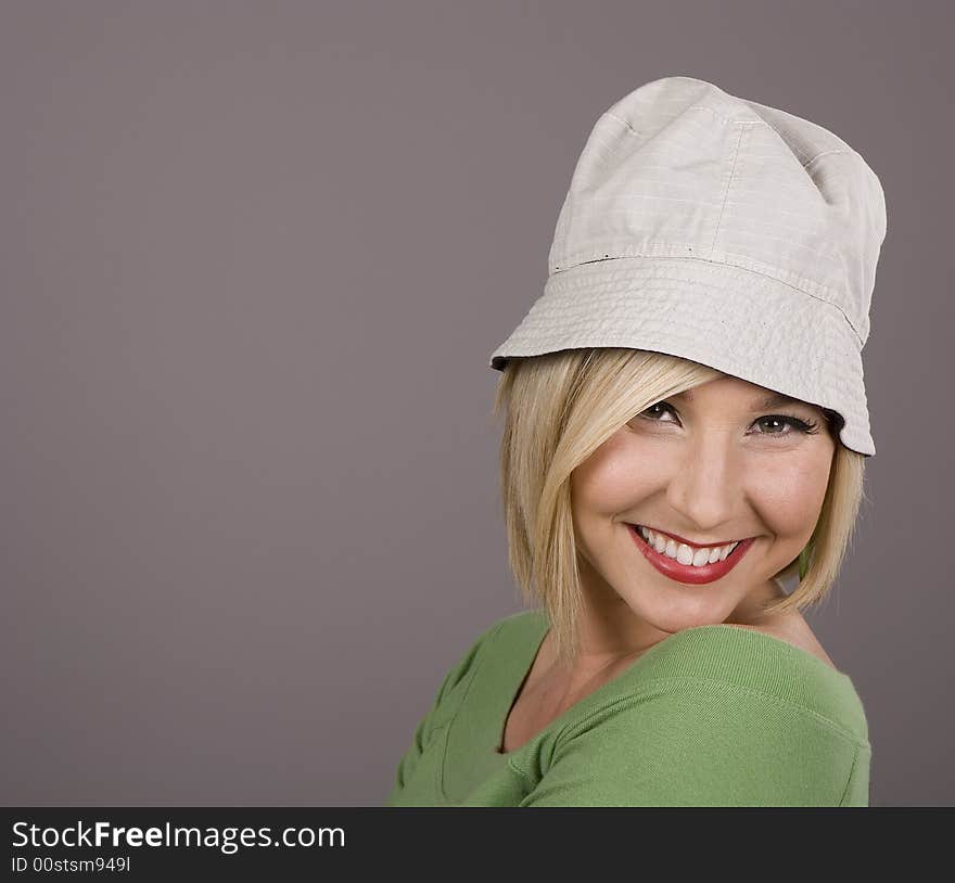 A blonde in a green blouse and silly white hat leaning back and smiling for the camera. A blonde in a green blouse and silly white hat leaning back and smiling for the camera