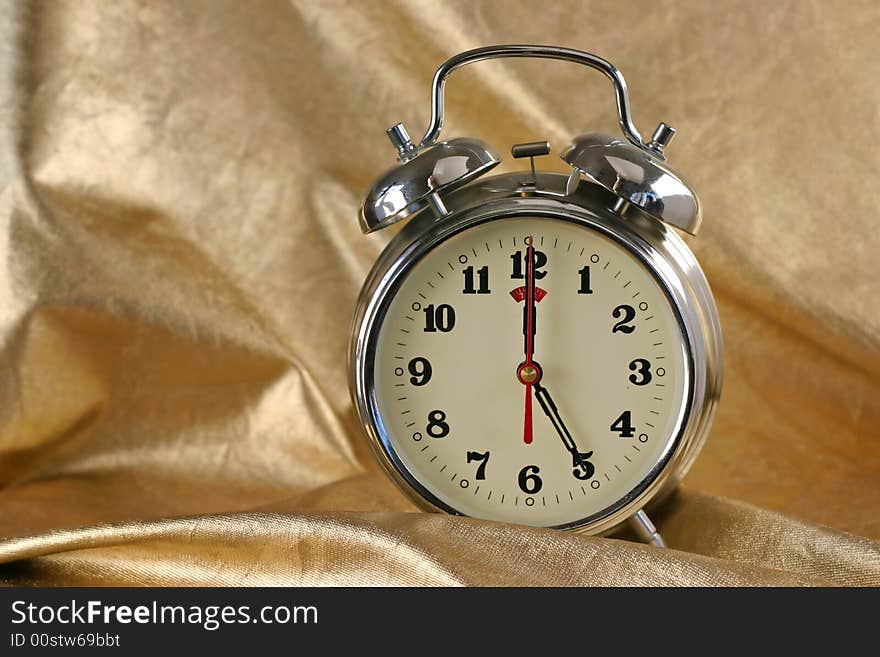 Metallic old-fashioned alarm-clock on gold background. Metallic old-fashioned alarm-clock on gold background