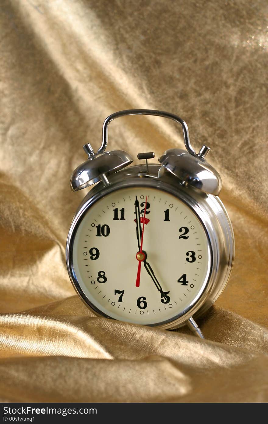 Metallic old-fashioned  alarm-clock on gold background. Metallic old-fashioned  alarm-clock on gold background