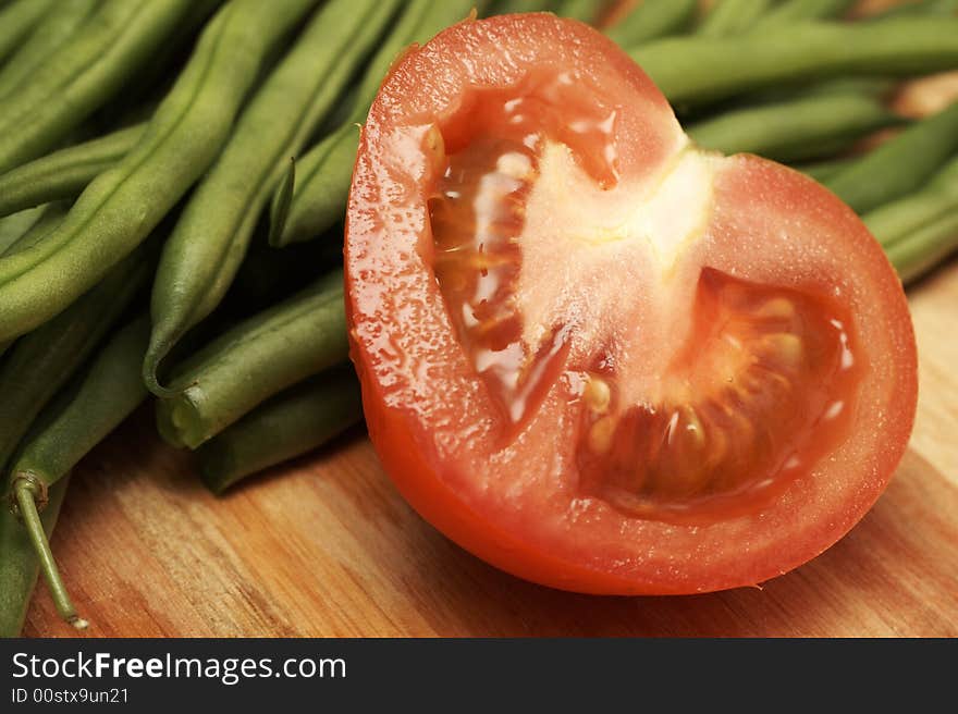 Juicy fresh sliced red tomato and green beans on wooden board. Juicy fresh sliced red tomato and green beans on wooden board