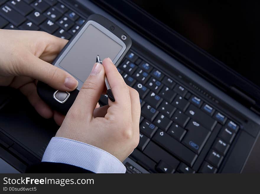 Businesswoman holding modern mobile pda phone with laptop in background