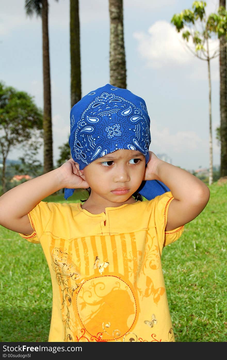 A little girl wearing bandana covering her head at the park. A little girl wearing bandana covering her head at the park.