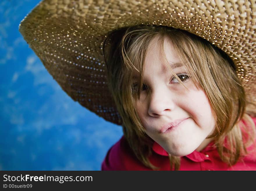 Little girl wearing a straw cowboy hat makes a funny face. Little girl wearing a straw cowboy hat makes a funny face