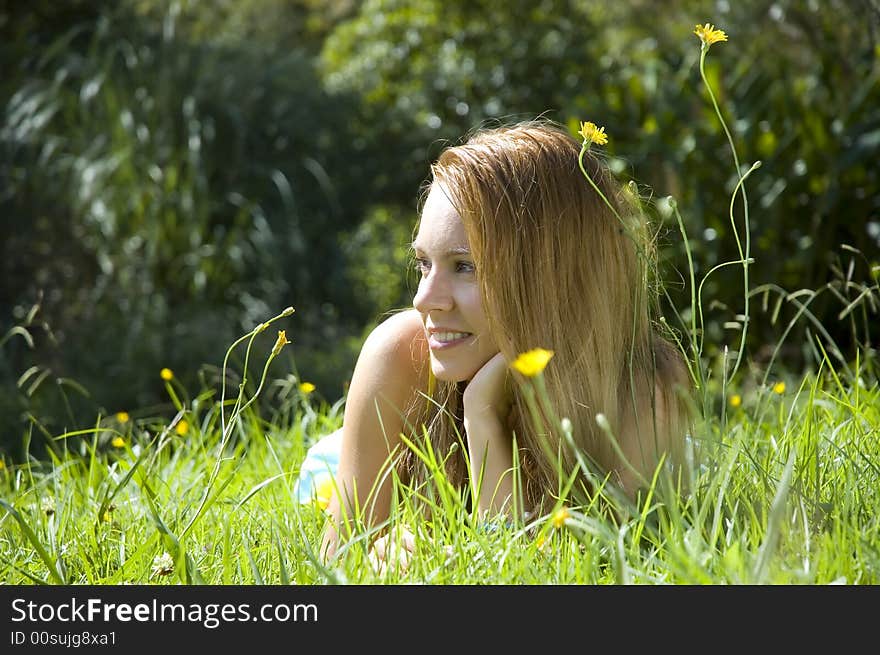 Happy beautiful young woman in green summer field