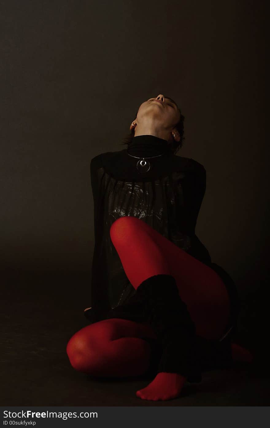 Silhouette of a nice girl in red stocks sitting on a floor