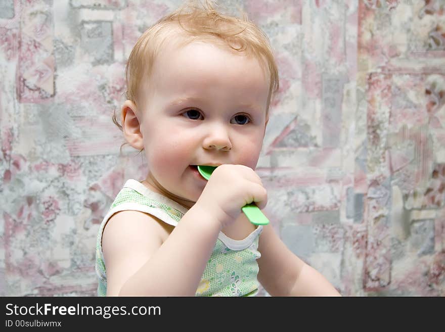 Baby with green spoon in hands. Baby with green spoon in hands