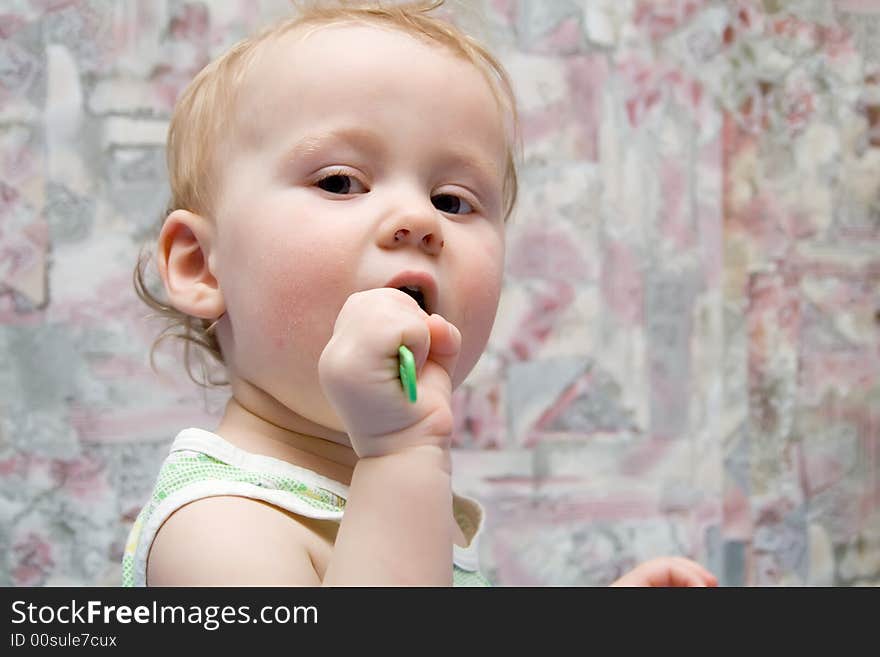 Baby with green spoon in hands. Baby with green spoon in hands