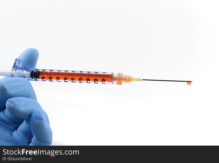 Gloved hand holding red liquid filled syringe with needle. Gloved hand holding red liquid filled syringe with needle