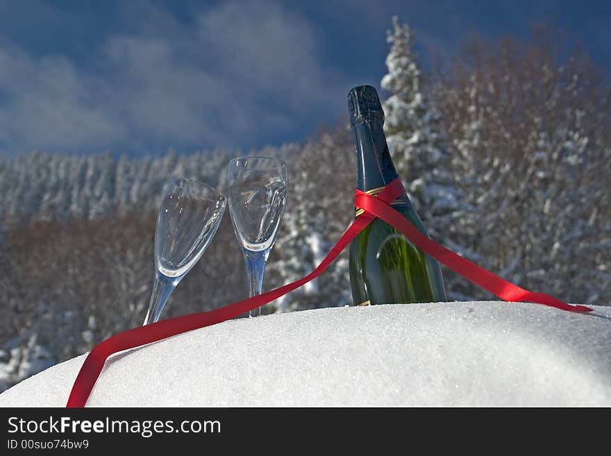 Glasses and bottle of champagne in snow