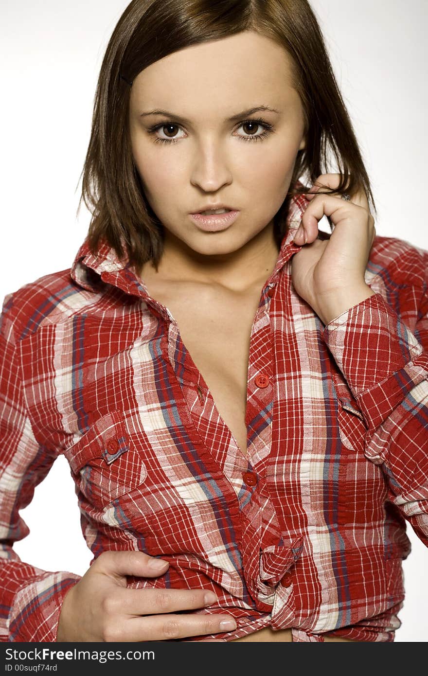 Close-up of beautiful brunette young girl wearingred and white blouse on light background