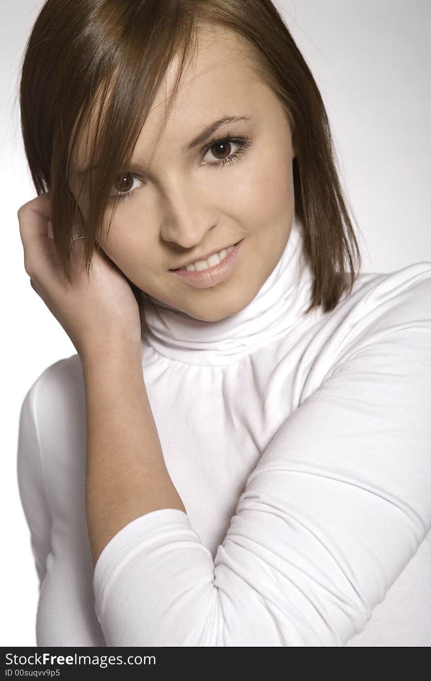 Close-up of beautiful brunette young girl wearing white blouse on light background