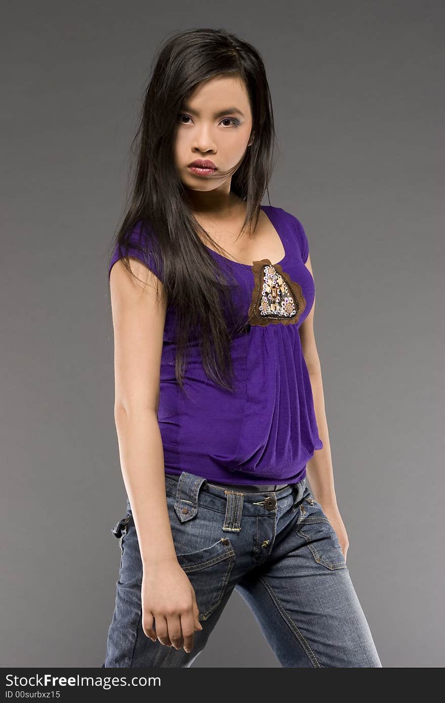 Studio shot of beautiful Asian model wearing purple blouse and jeans