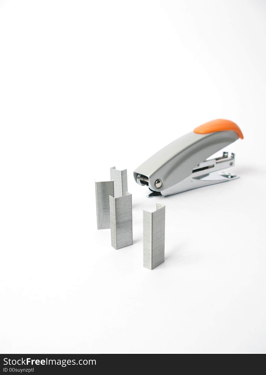 Silver and orange Stapler with staples on white background