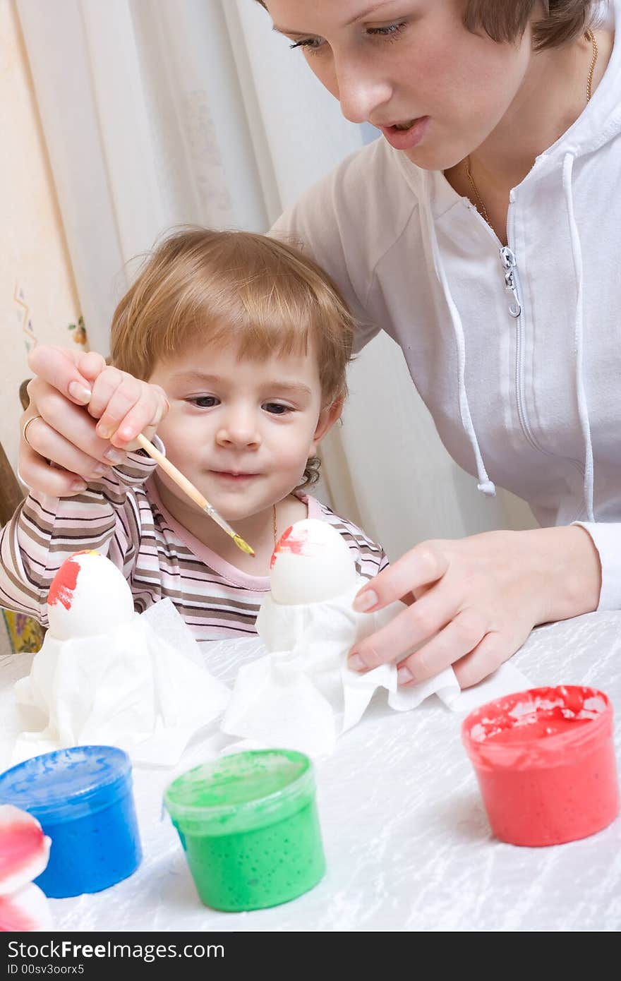 Little child painting eggs before easter