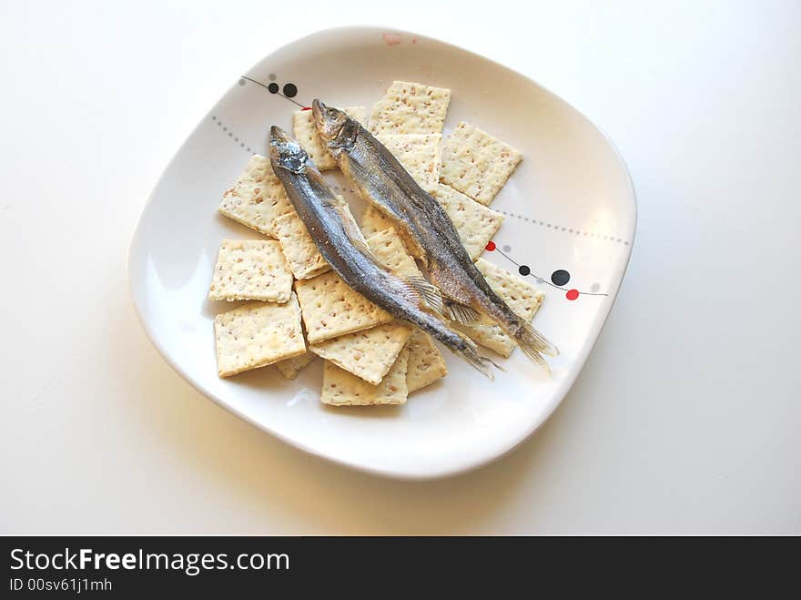 Dry small fishes and crackers on a dish. Dry small fishes and crackers on a dish.