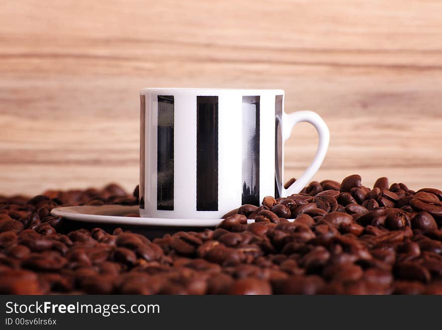 Some coffee beans and a jute sack behind a cup of black coffee. Some coffee beans and a jute sack behind a cup of black coffee