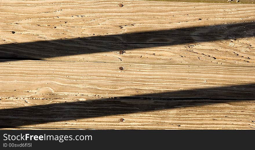 Shadows running across old weathered, sandy planks on a beach boardwalk. Shadows running across old weathered, sandy planks on a beach boardwalk