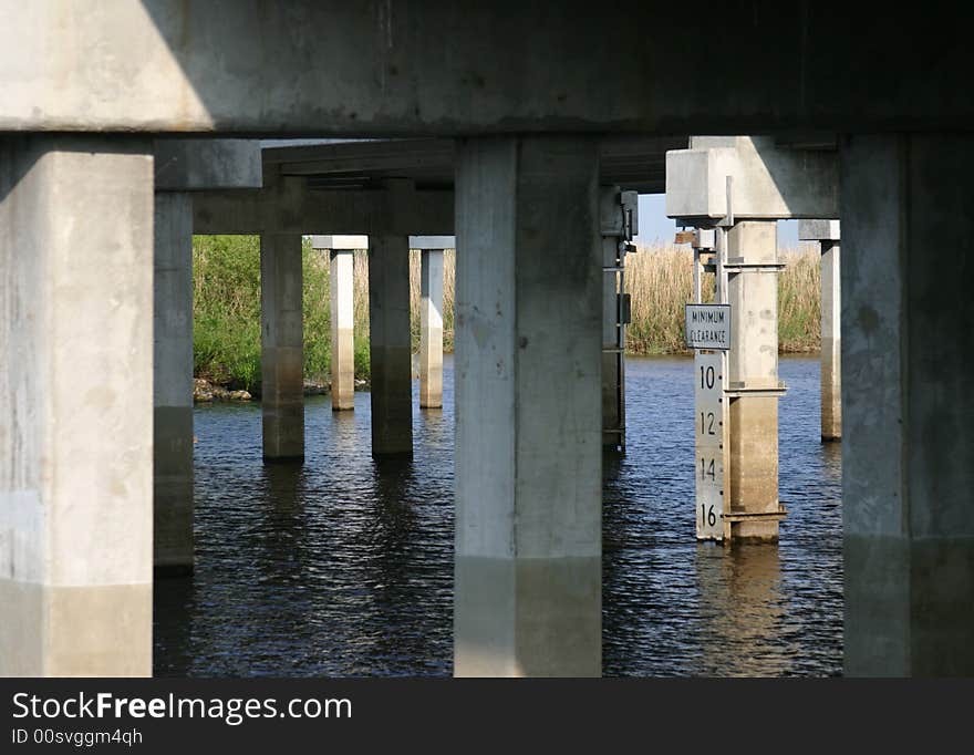 Highway bridge over the Saint John's River, Florida. Shot from below showing cluster of support pilings, river and underside of roadway. Center of focus is on the river depth gauge attached to one of the support posts