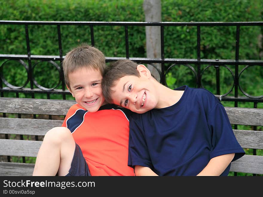 Brothers Smiling Sitting on a Park Bench