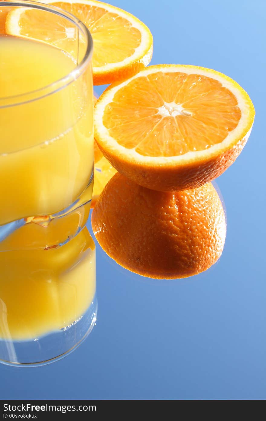 Glass of orange juice and incised orange on blue background. Glass of orange juice and incised orange on blue background