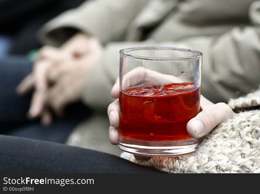 An image of a person's hand with a glass of spirits. An image of a person's hand with a glass of spirits