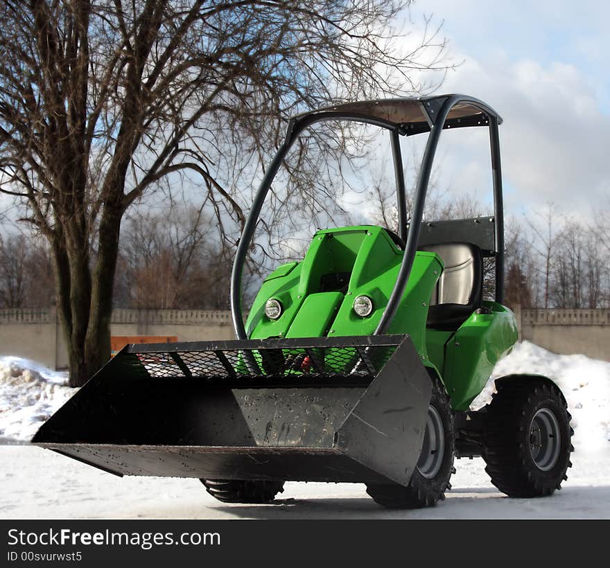 Green excavator on white snow