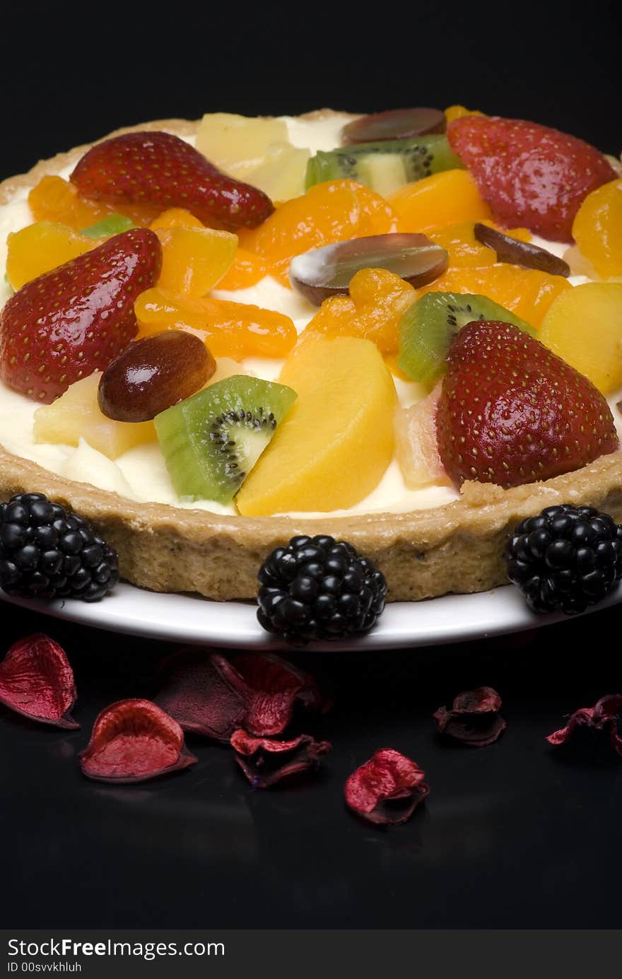 A fruit pie on a white plate on a black background