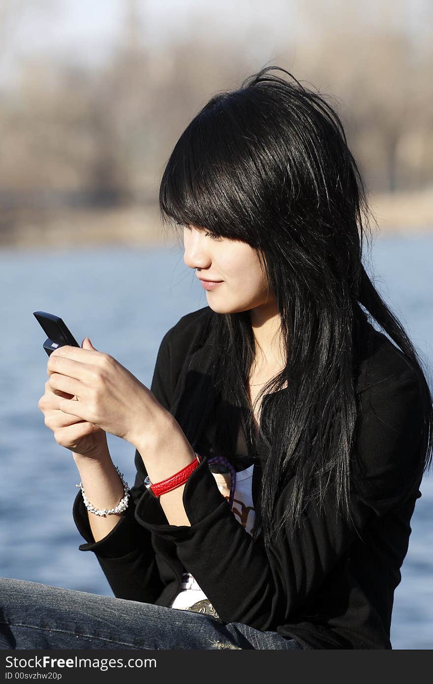 This Chinese girl is looking over the information in her mobile phone. This Chinese girl is looking over the information in her mobile phone.