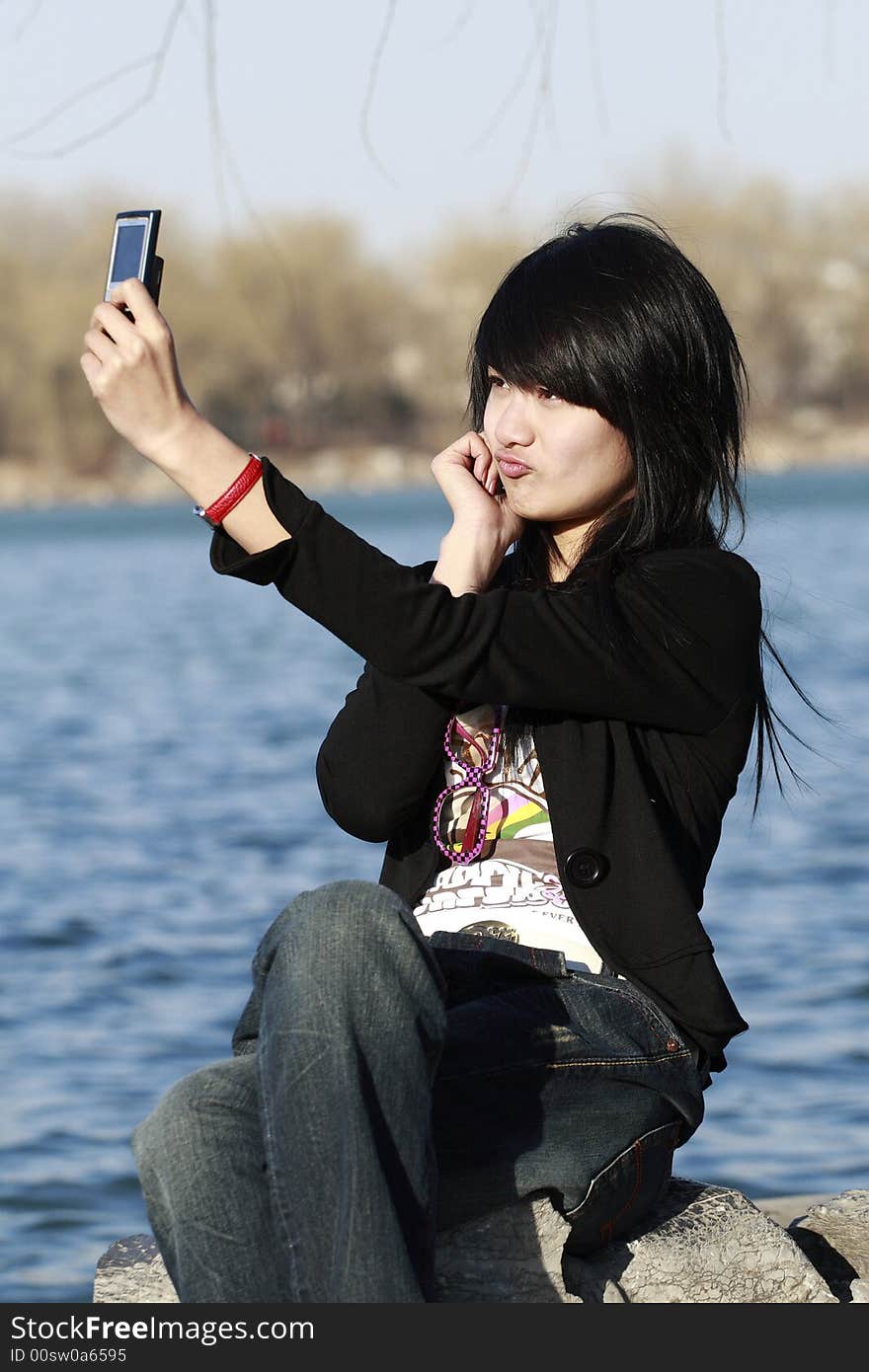 A beautiful Chinese girl shoots herself with the mobile phone happily.The appearance of making faces is very lovely. A beautiful Chinese girl shoots herself with the mobile phone happily.The appearance of making faces is very lovely.