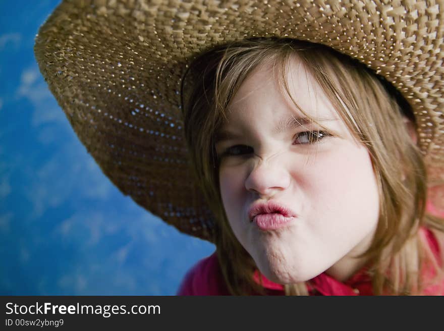 Little girl wearing a straw cowboy hat makes a funny face. Little girl wearing a straw cowboy hat makes a funny face