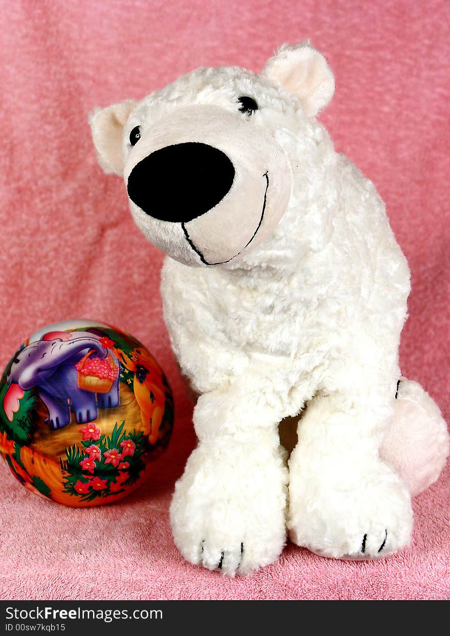 White teddy bear and ball on pink background