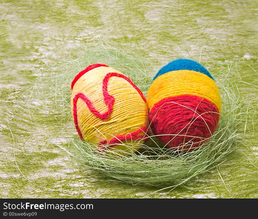 Easter eggs in green nest and green background. Eggs to be decorated colored yarn.