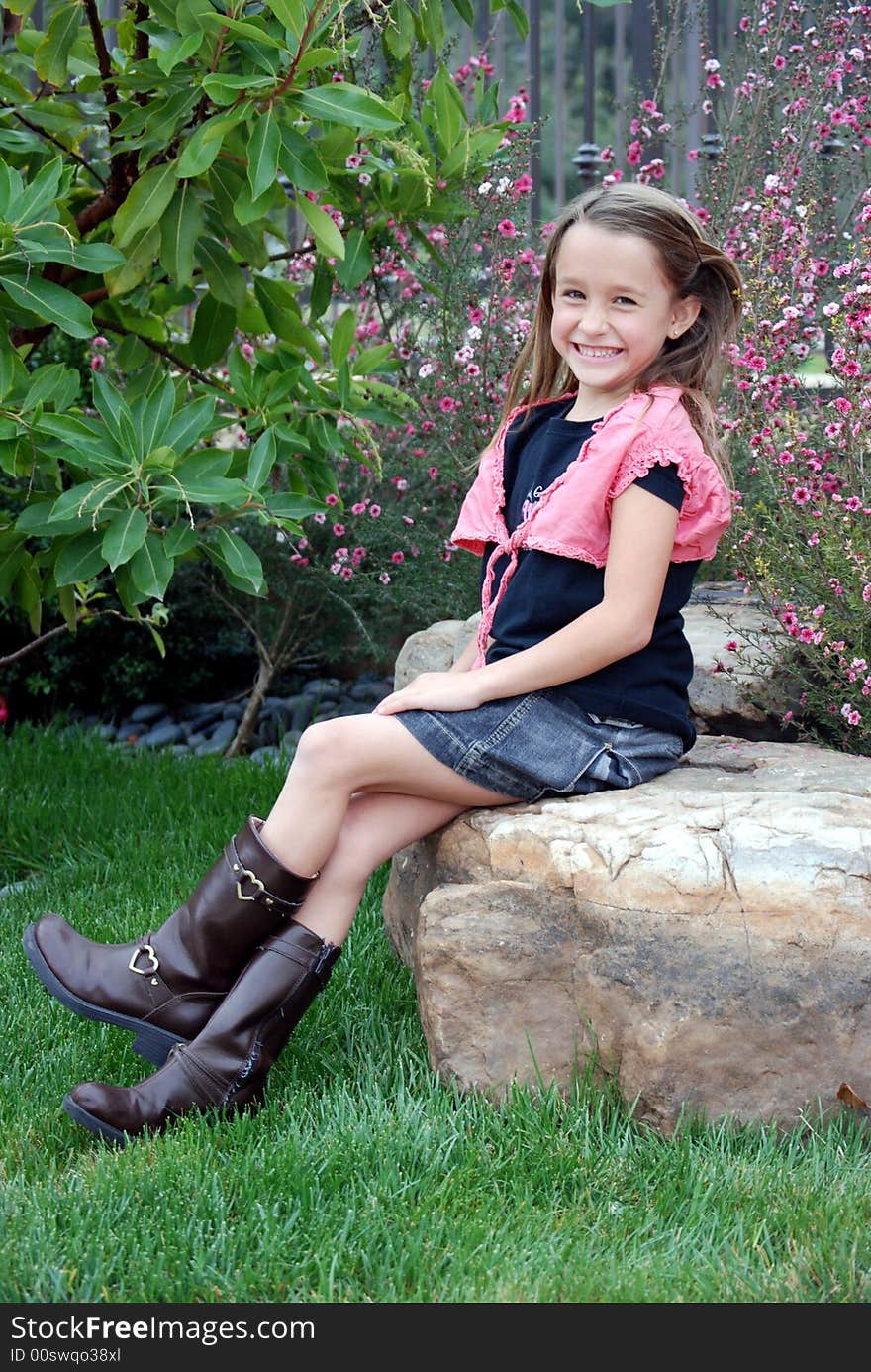 Little girl sitting on a rock, being silly. Little girl sitting on a rock, being silly