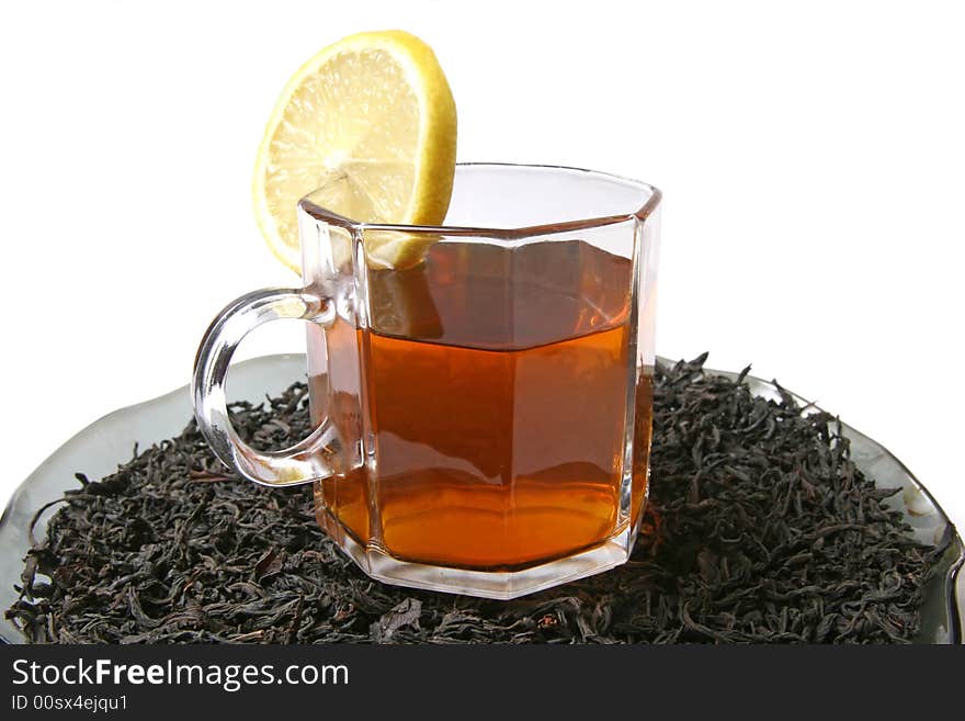 A cup of tea with a lemon on a black tea leaves