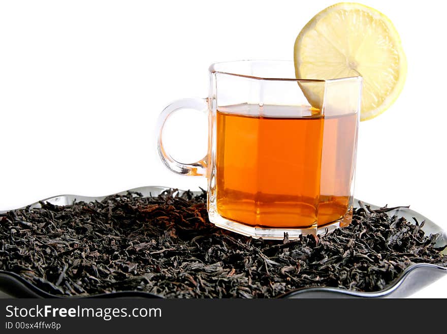 A cup of tea with a lemon on a black tea leaves