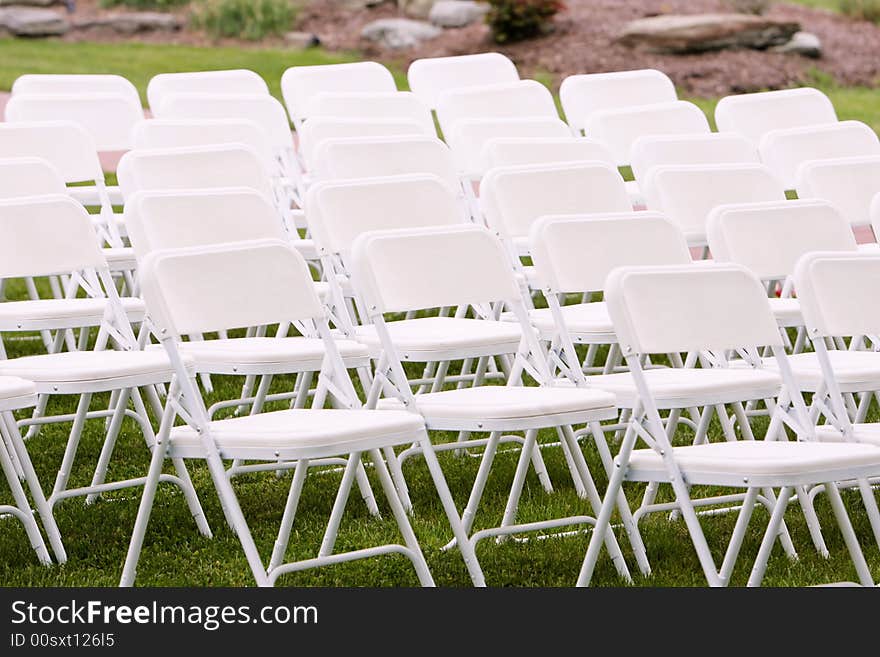 White chairs arranged and setup for a wedding ceremony. White chairs arranged and setup for a wedding ceremony