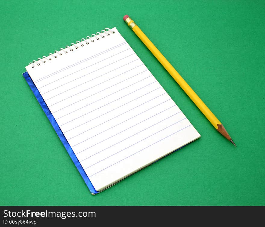 Yellow pen besides an open notebook on a green surface. Yellow pen besides an open notebook on a green surface